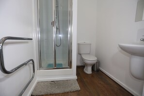 A bathroom with a glass shower enclosure, a white toilet, and a white sink.