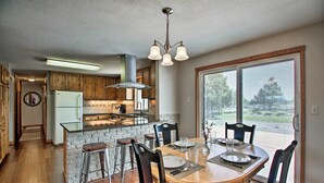 Una cocina moderna con armarios de madera, una isla central y un comedor con un ventanal grande.