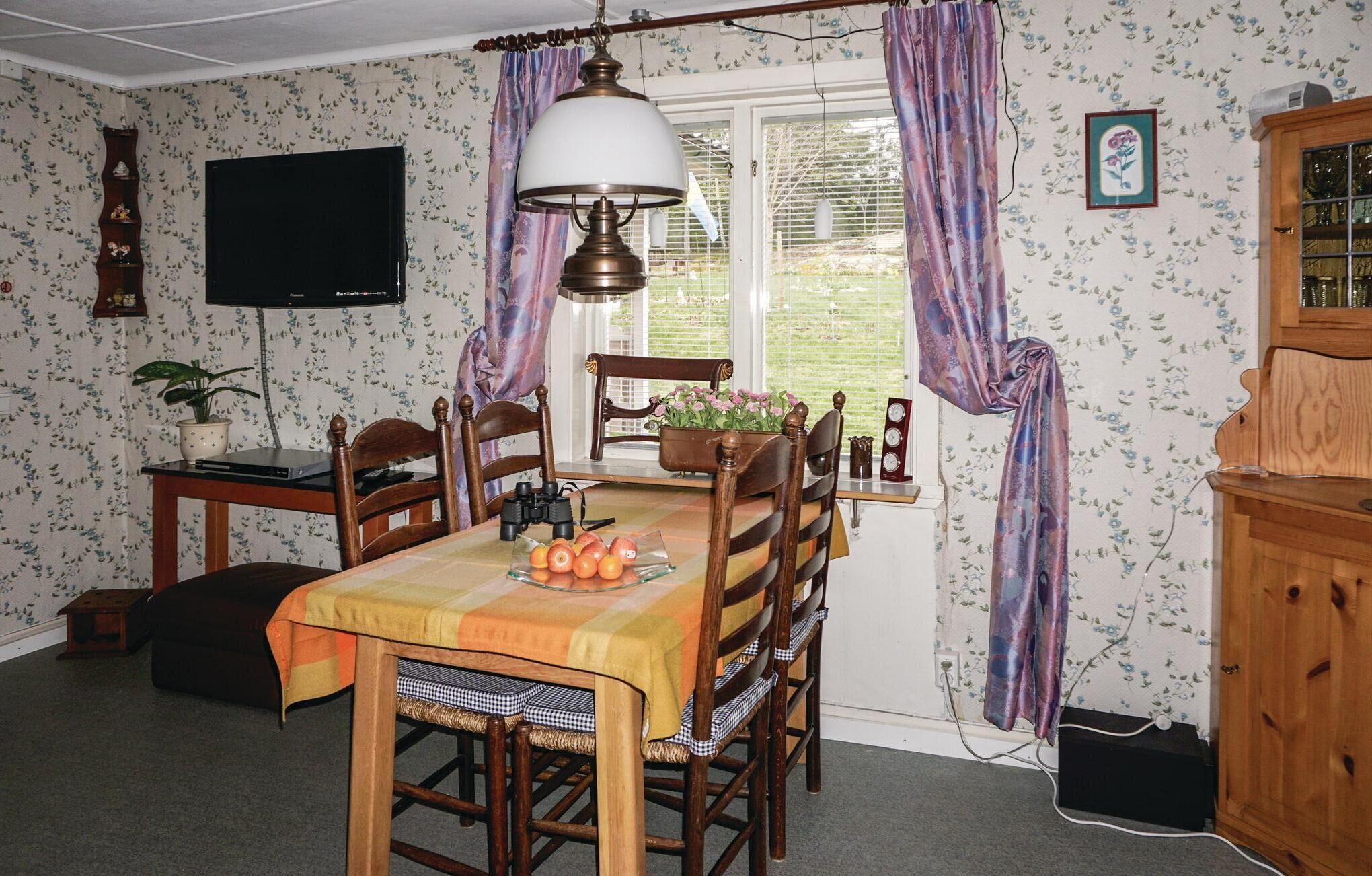 Un coin repas avec une table dressée pour quatre personnes, un buffet en bois et un téléviseur fixé au mur.