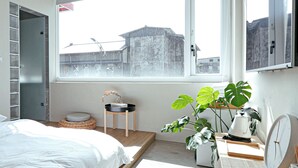 A bedroom with a bed, a small stool, a potted plant, a kettle, and a clock. - Hostel Tomato (Jiaoxi)