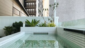 A modern indoor swimming pool with tiled walls and a geometric floor pattern. - Hostel Tomato (Jiaoxi)