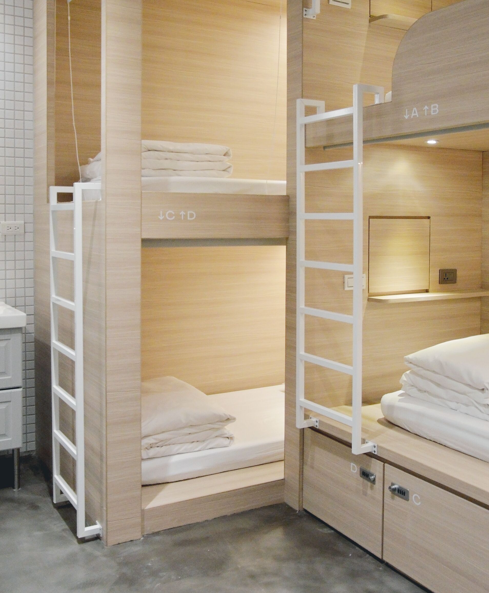 A bunk bed room with a ladder, a shelf with folded towels, and a small cabinet with a lock.