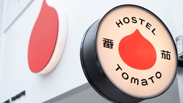 A circular sign with the words "HOSTEL" and "Tomato" indicating a hostel with a tomato-themed design. - Hostel Tomato (Jiaoxi)