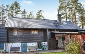 A log cabin with a tiled roof, a chimney, and a small porch area with a bicycle and a bench. - Beautiful home in Tidaholm with sauna (Tidaholm)