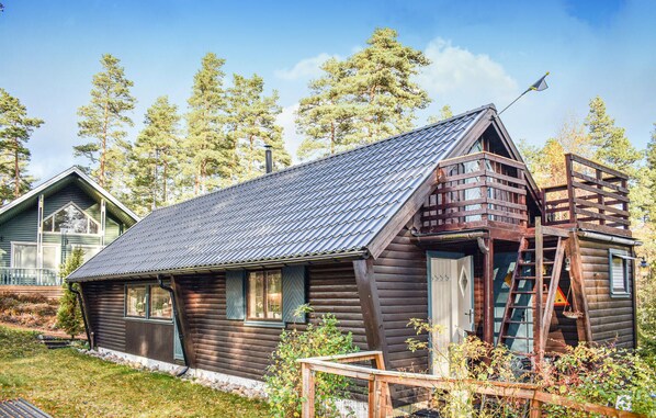 A rustic log cabin with a metal roof, a wooden deck, and a ladder leading to a loft area. - Beautiful home in Tidaholm with sauna (Tidaholm)