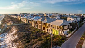 Un quartier résidentiel situé sur la côte, avec des maisons construites le long de la plage, comprenant une route asphaltée et une promenade.