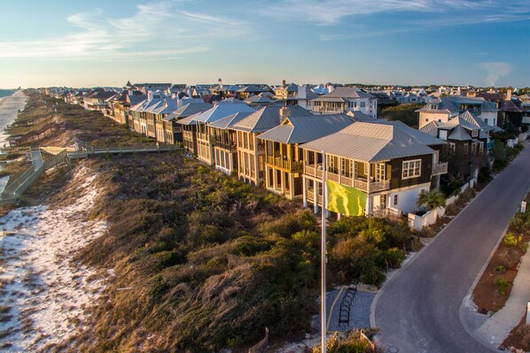 A coastal residential area with houses along the beach, featuring a paved road and a walkway.