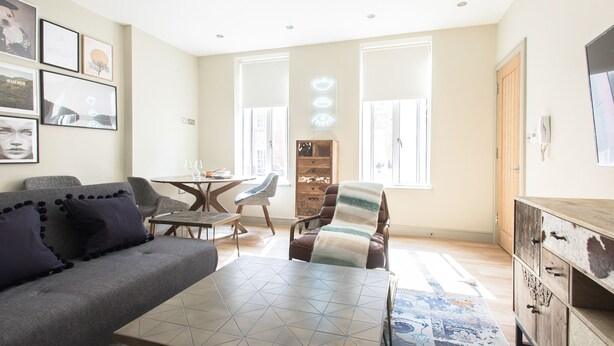 Un salon moderne comprenant un canapé, un fauteuil, une table basse et un meuble en bois.