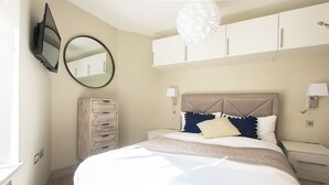 Une chambre à coucher avec un lit, une commode, un miroir et un ventilateur de plafond.