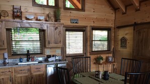 Cocina rústica de madera con una mesa de comedor, sillas y una estación de café.
