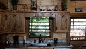 Una cocina rústica con armarios de madera, un lavavajillas de acero inoxidable y una ventana con persianas.