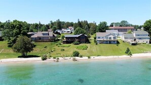 A coastal residential area with houses on a hillside overlooking a clear, turquoise beach. - Huron Haven in St. Ignace (Saint Ignace)