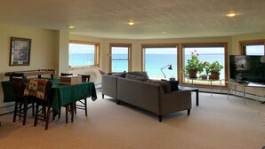 A living room with a pool table, sofa, and a TV. There are large windows with a view of the sea. - Huron Haven in St. Ignace (Saint Ignace)