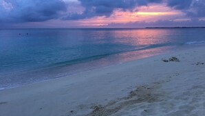 Ein Strand mit ruhigem Wasser und einem Sonnenuntergangshimmel.