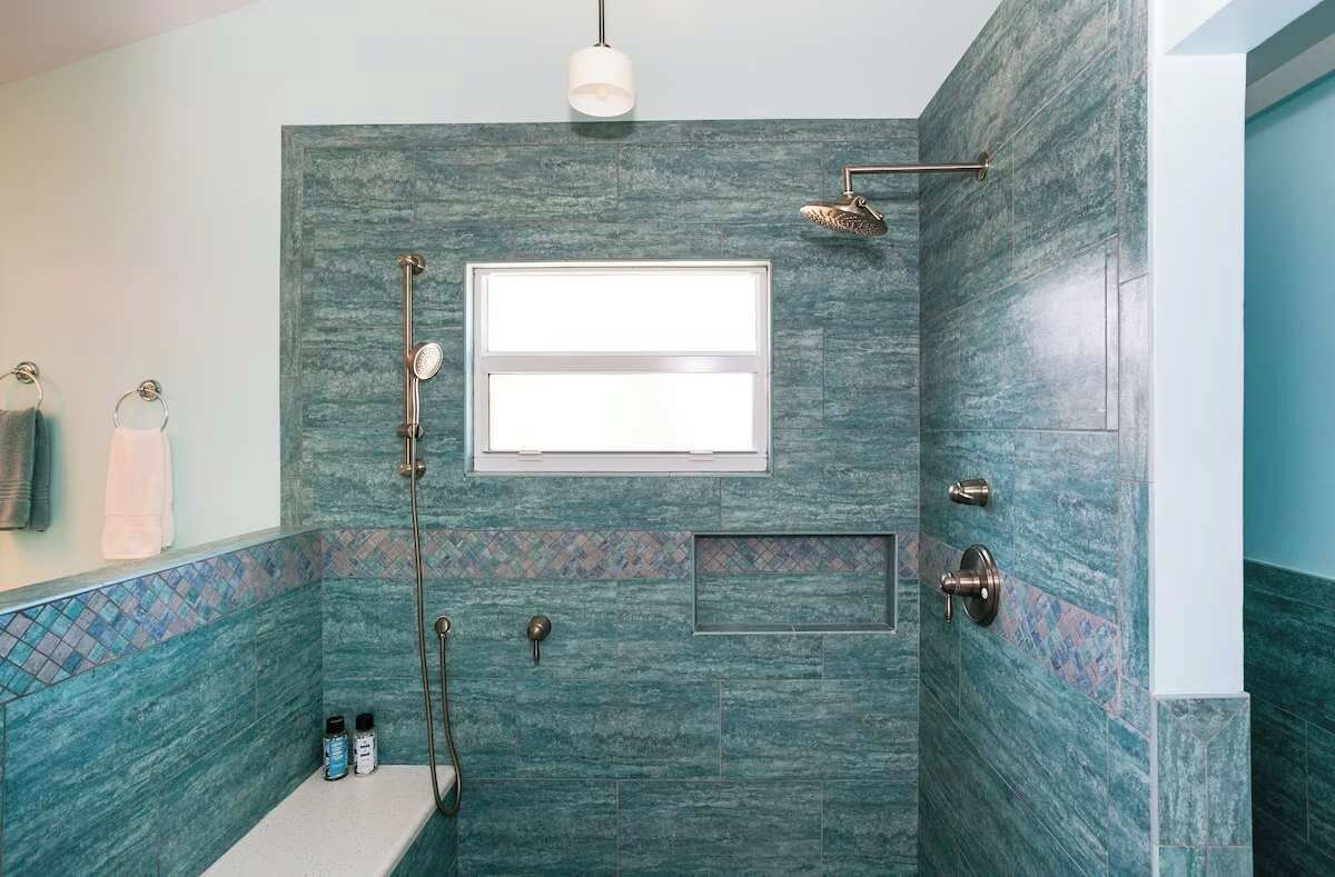 A bathroom with a shower, a towel rack, and a window.