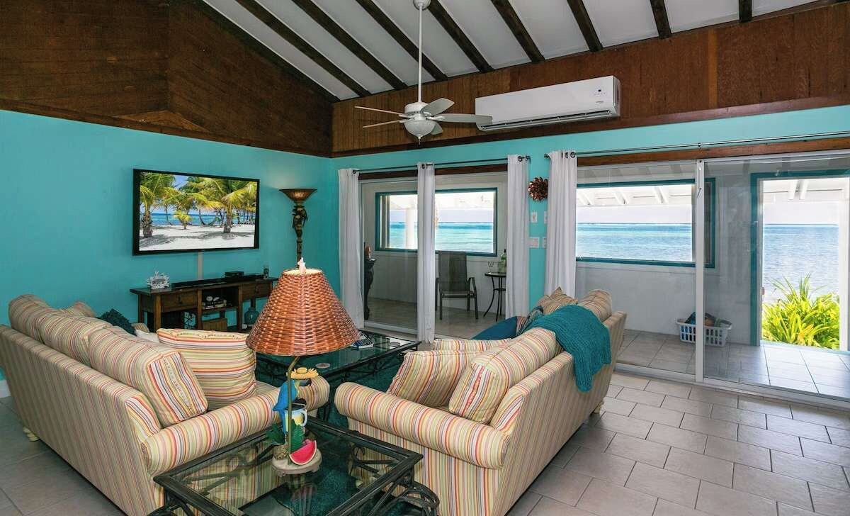 A living room with striped sofas, a glass coffee table, and a ceiling fan.