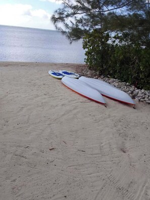 A sandy beach with two surfboards and a rocky shoreline.