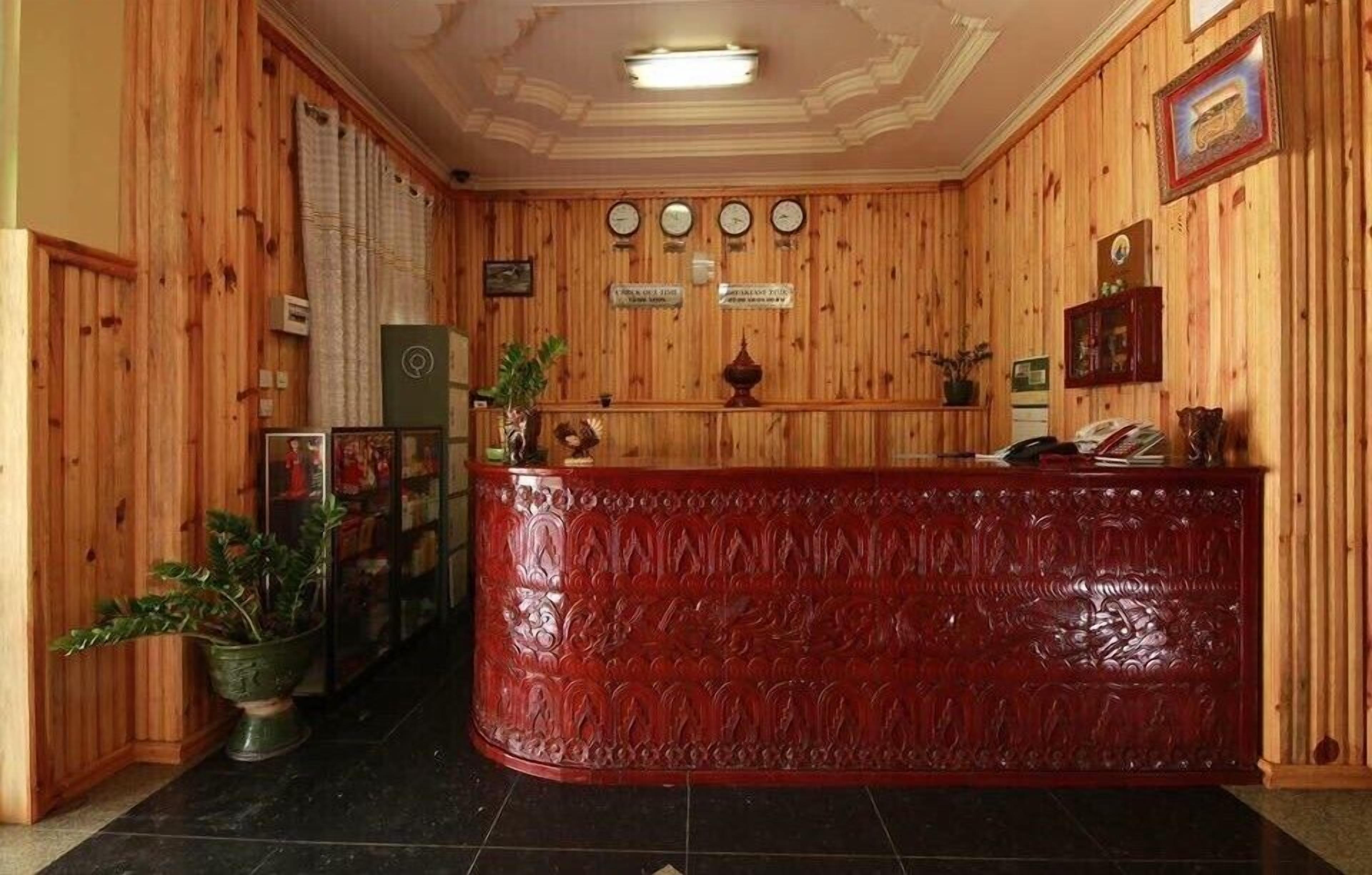 Zona de recepción con interior de madera, un mostrador de recepción y un reloj en la pared.