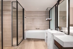 A modern bathroom with a glass shower enclosure, a freestanding bathtub, and a vanity with a large mirror.