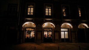 A building with three illuminated entrances, each with a glass door and a small balcony. - Exmo Hotel by Olivia (Porto)