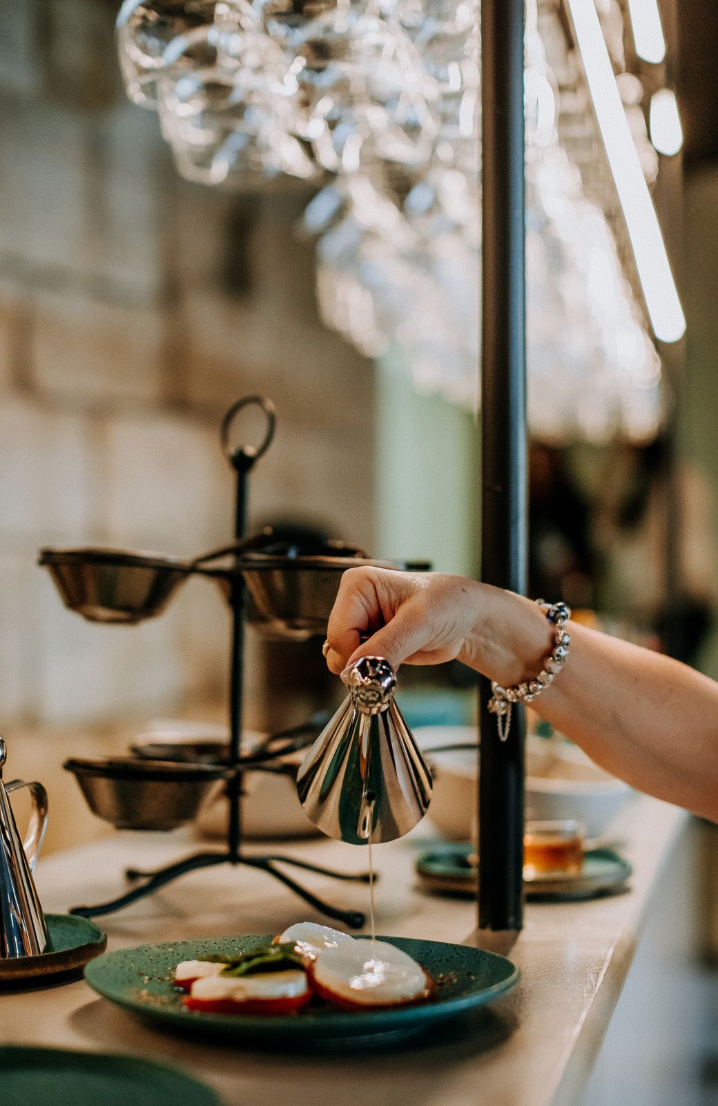 A hand pouring a liquid from a bottle into a green plate with food.