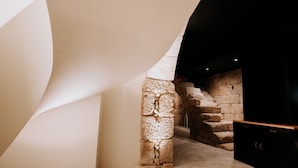 Un intérieur moderne avec un mur en pierre et un plafond blanc aux lignes courbes.