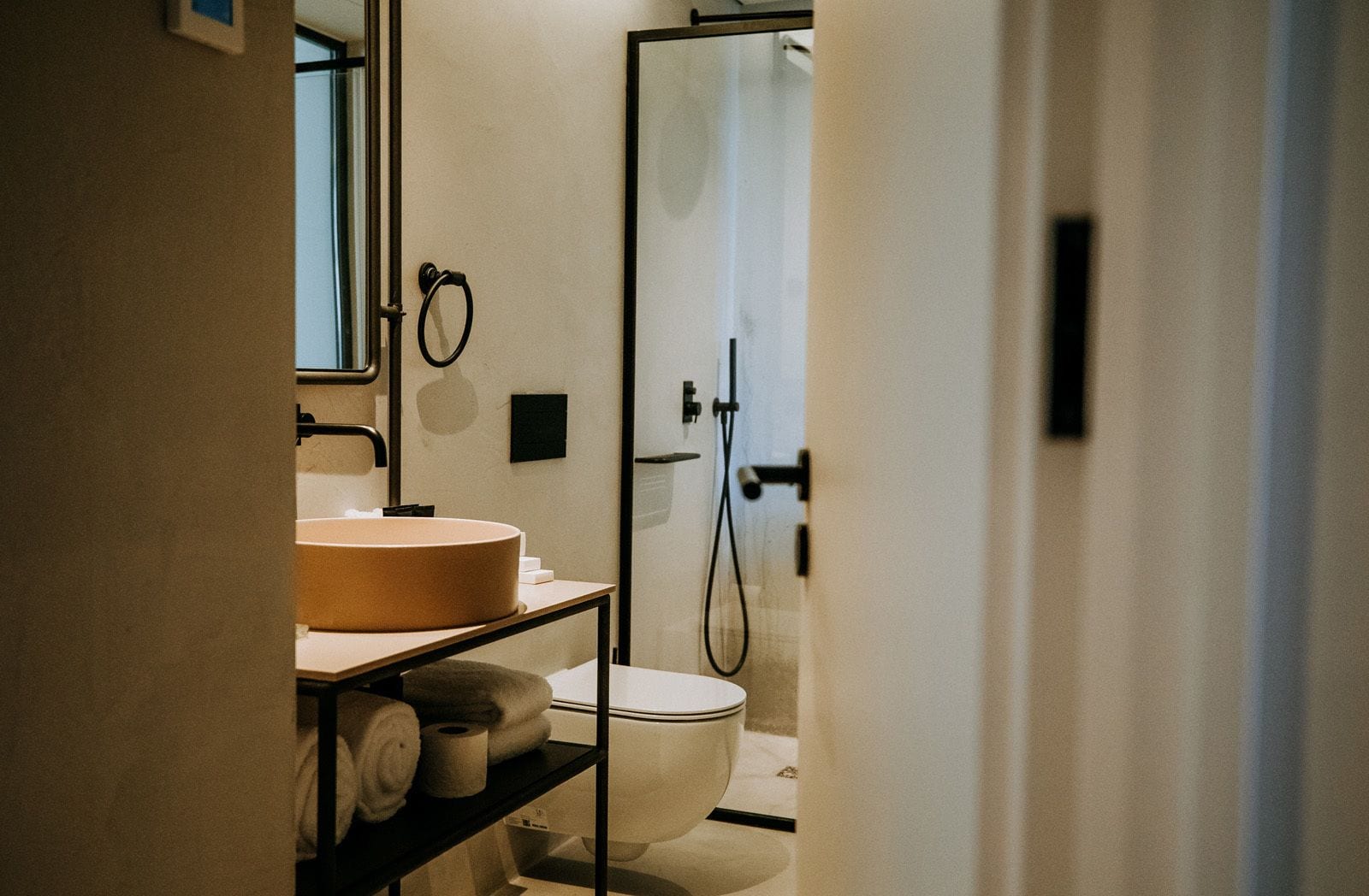 A modern bathroom with a round sink, toilet, and glass shower enclosure.