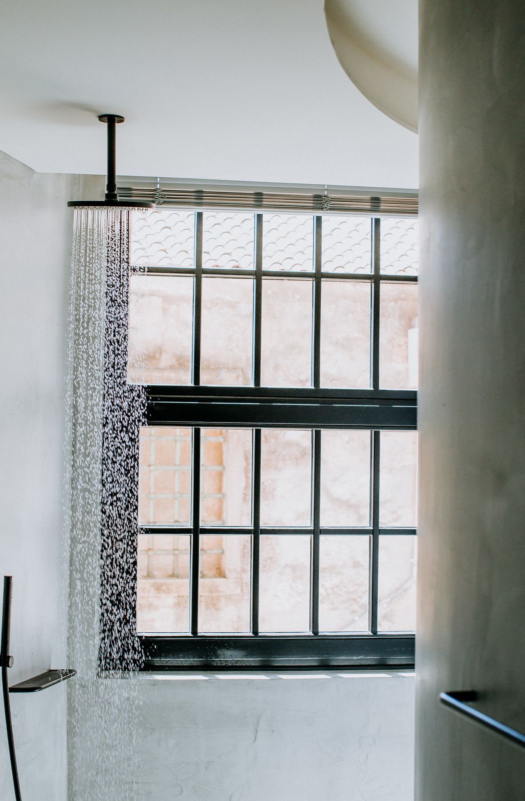 A shower with a black metal frame and a window with a grid pattern.