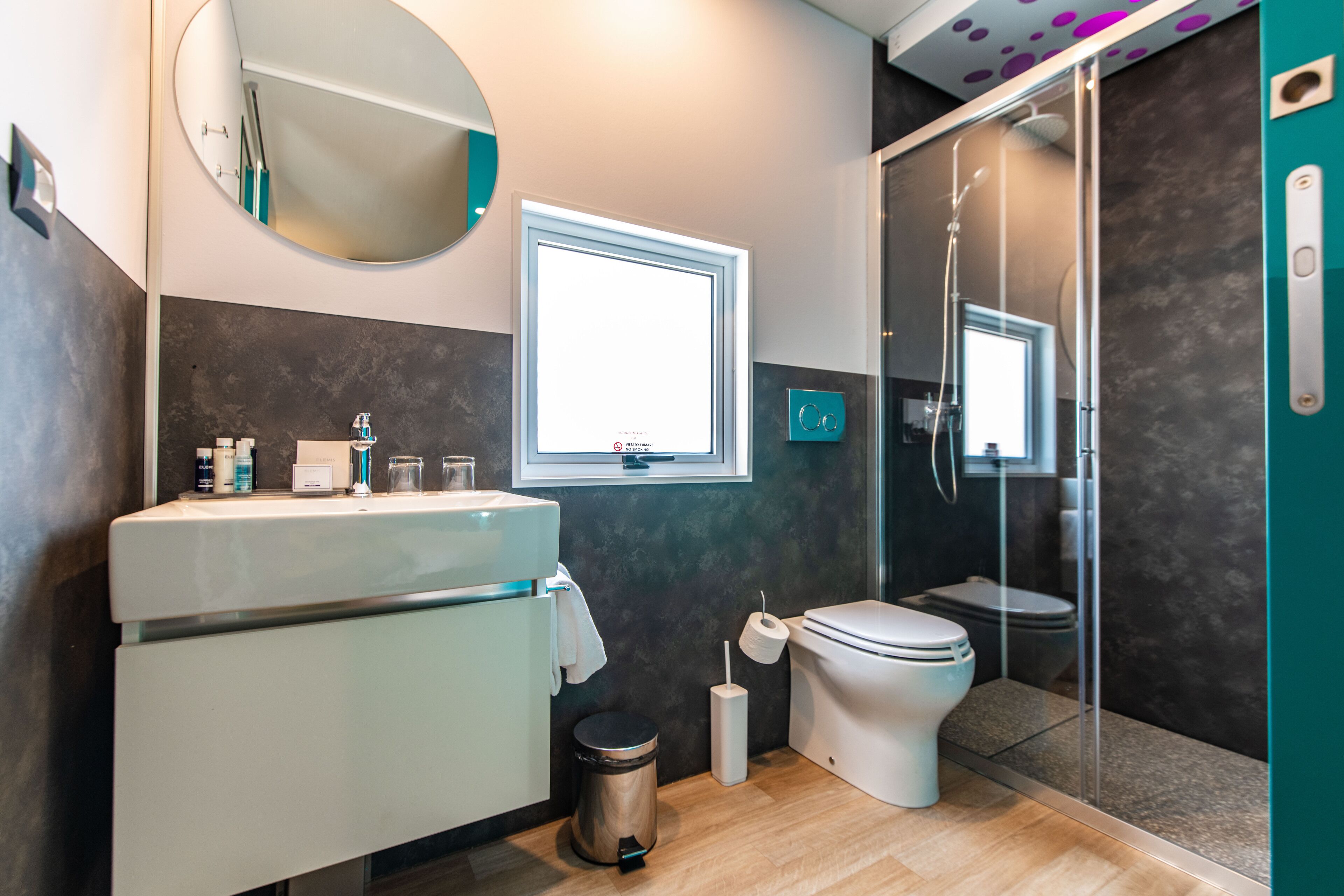 A modern bathroom with a white sink, a toilet, and a glass-enclosed shower.
