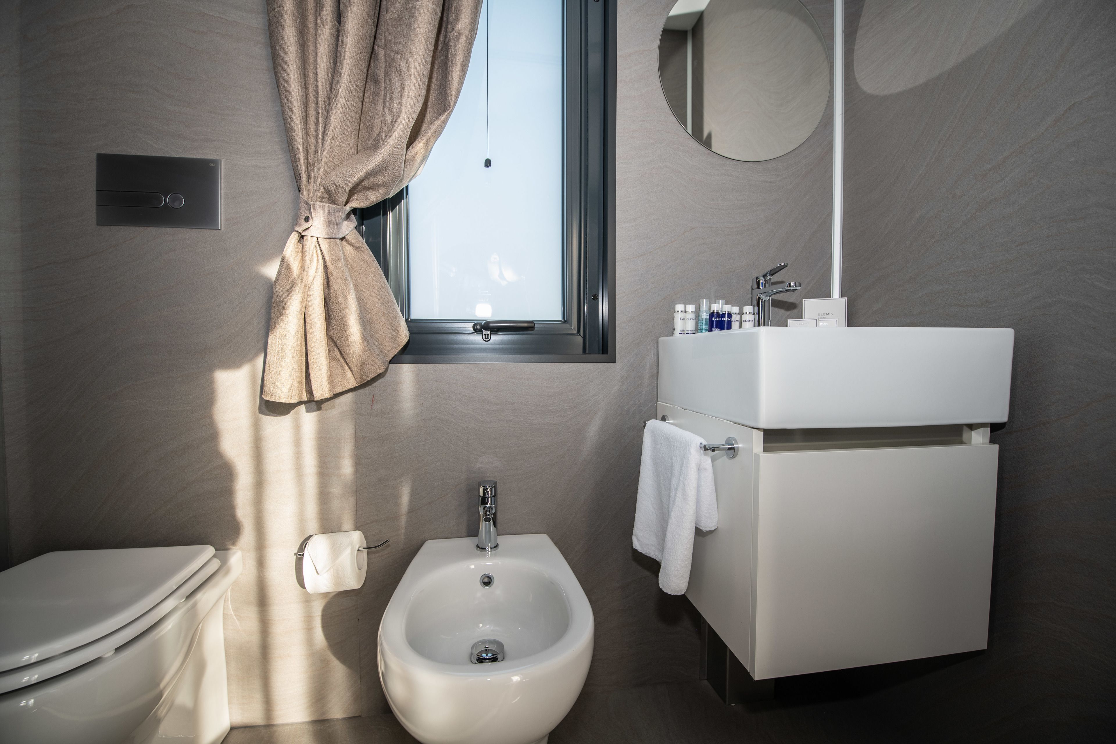 A modern bathroom with a toilet, bidet, and a sink with a mirror.