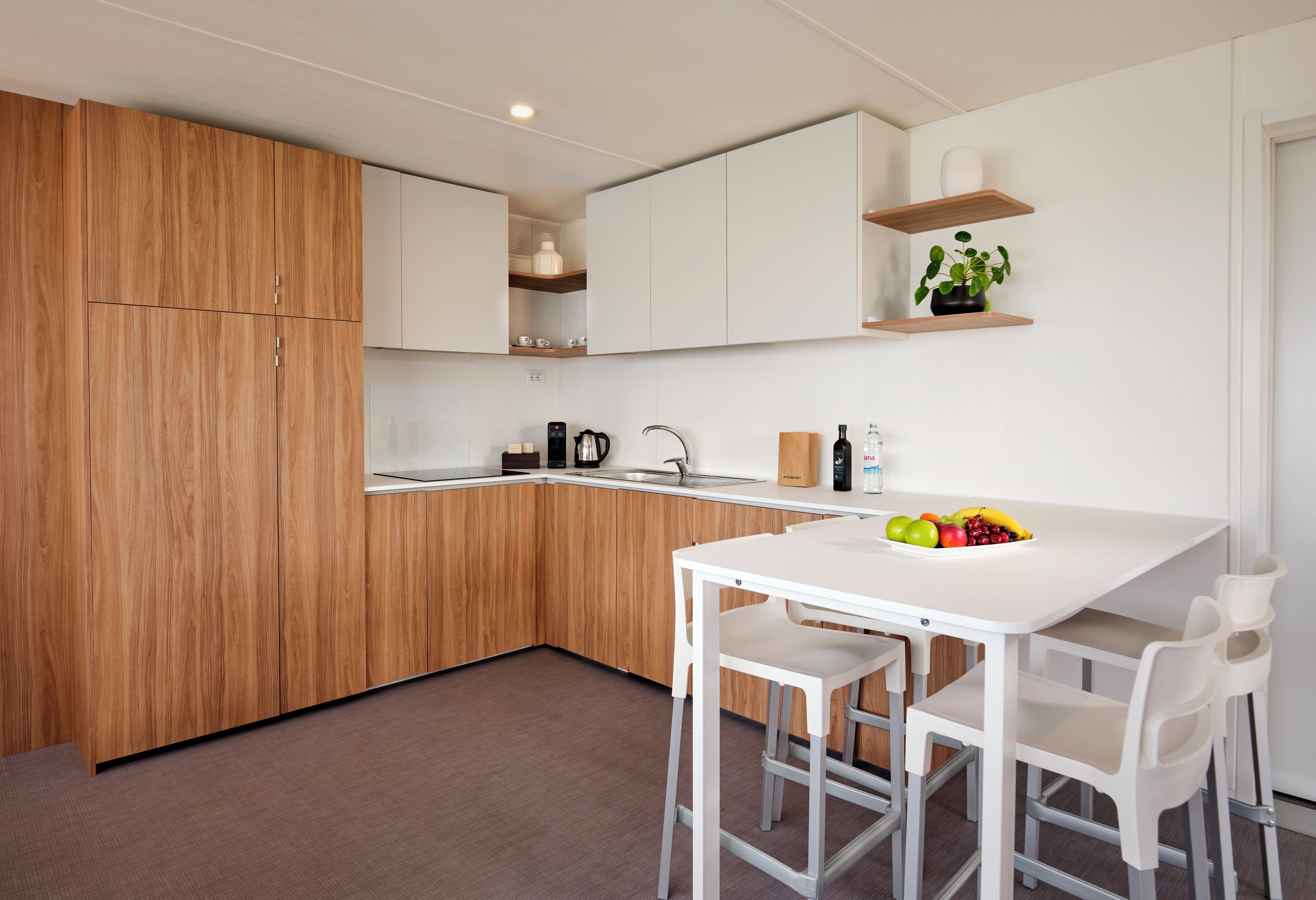 Une cuisine moderne avec des meubles en bois, un plan de travail blanc et une table à manger blanche avec des chaises.