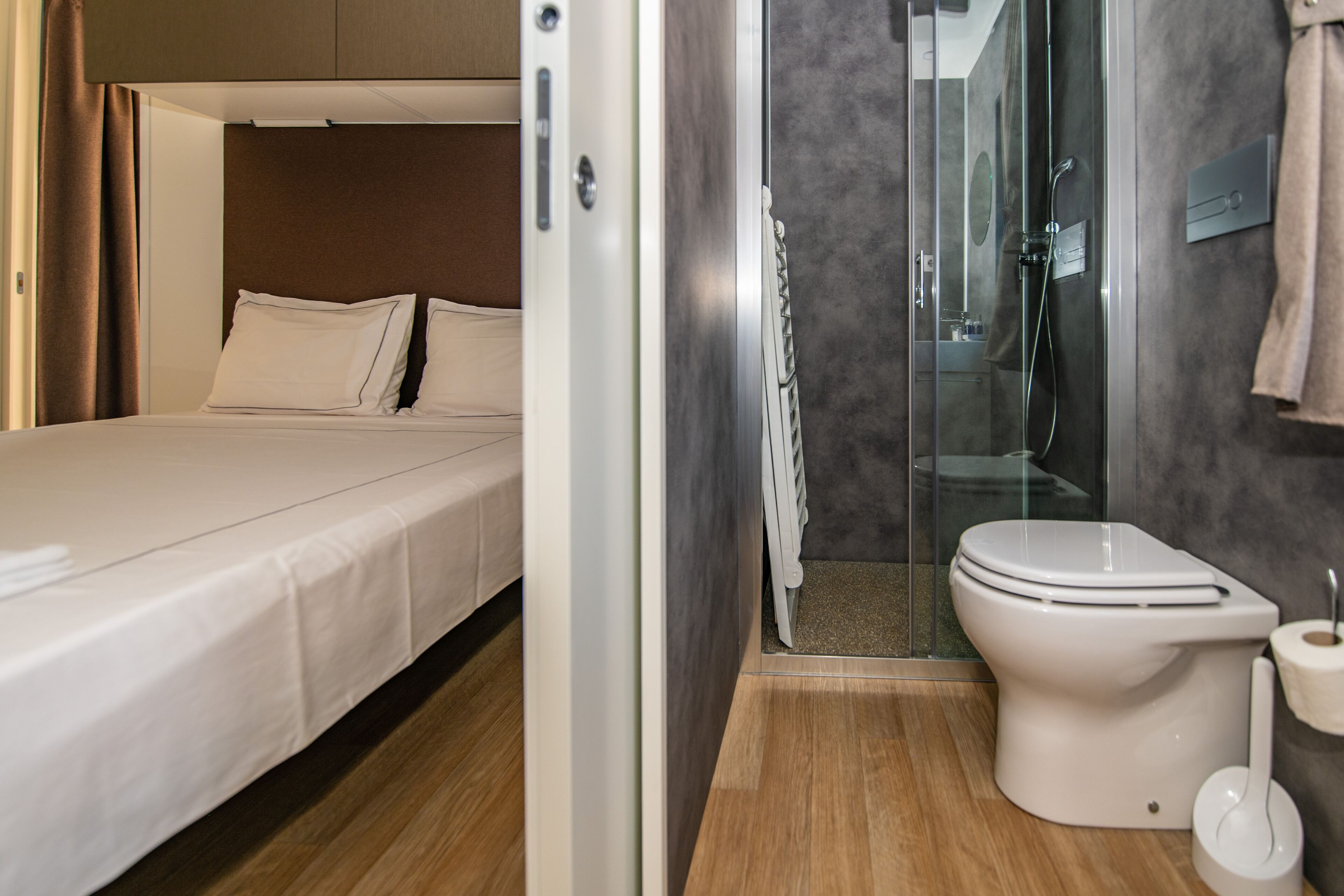 Une chambre d’hôtel de taille réduite, comprenant un lit, un espace douche et des toilettes.