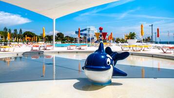 A pool area with a dolphin statue, lounge chairs, and umbrellas.