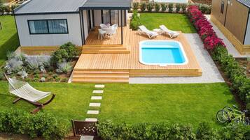 Une terrasse extérieure moderne avec une piscine, des chaises longues et un hamac.
