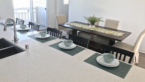 Eine moderne Küche mit einer zentralen Kochinsel, einer eingebauten Spüle und einem Essbereich mit Tisch und Stühlen.