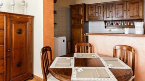Un coin repas avec une table en bois, quatre chaises et une cuisine en arrière-plan.