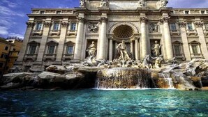 Un imposant bâtiment, orné d’une grande fontaine à l’avant, avec des statues et un élément architectural circulaire.