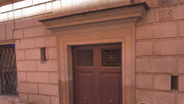 Une porte marron avec une grille en métal et une petite fenêtre au-dessus.