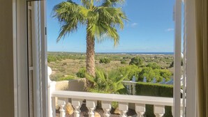 A balcony with a white balustrade, a palm tree, and a view of a coastal landscape. - Amazing home in Quesada-Rojales (Quesada-Rojales)