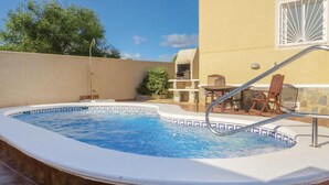 A swimming pool with a tiled edge, a metal ladder, and a patio area with chairs and a table. - Amazing home in Quesada-Rojales (Quesada-Rojales)