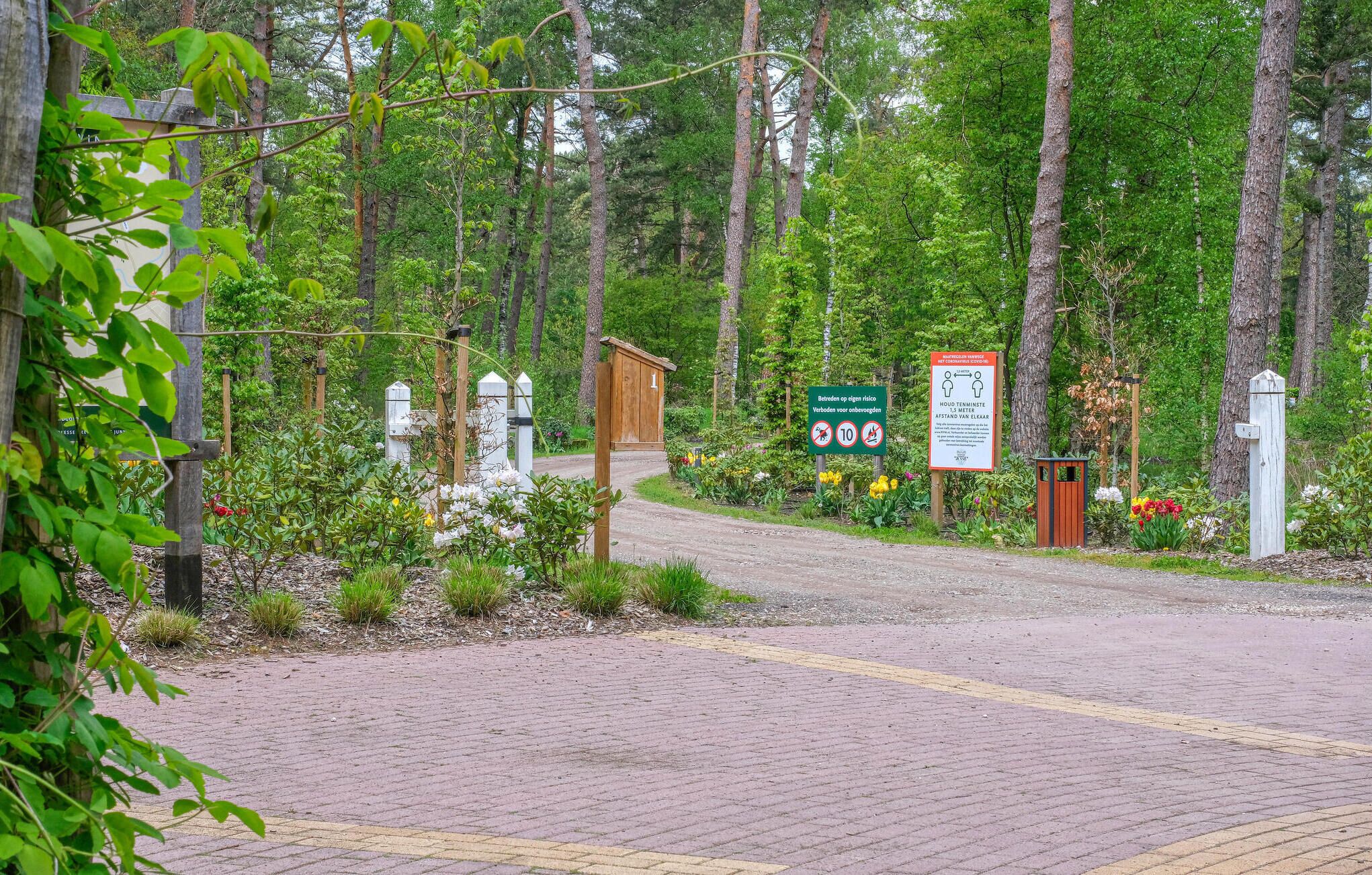 Un sendero pavimentado que se adentra en una zona boscosa con una estructura de madera que dice '1'.