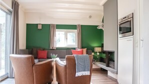 A living room with a sofa, two armchairs, a fireplace, and a large window.