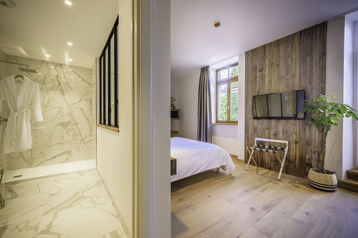 Un dormitorio moderno con ducha de mármol, pared de madera, cama y televisor.
