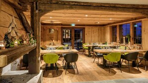 Interior de madera con mesas dispuestas para comer, sillas y chimenea.
