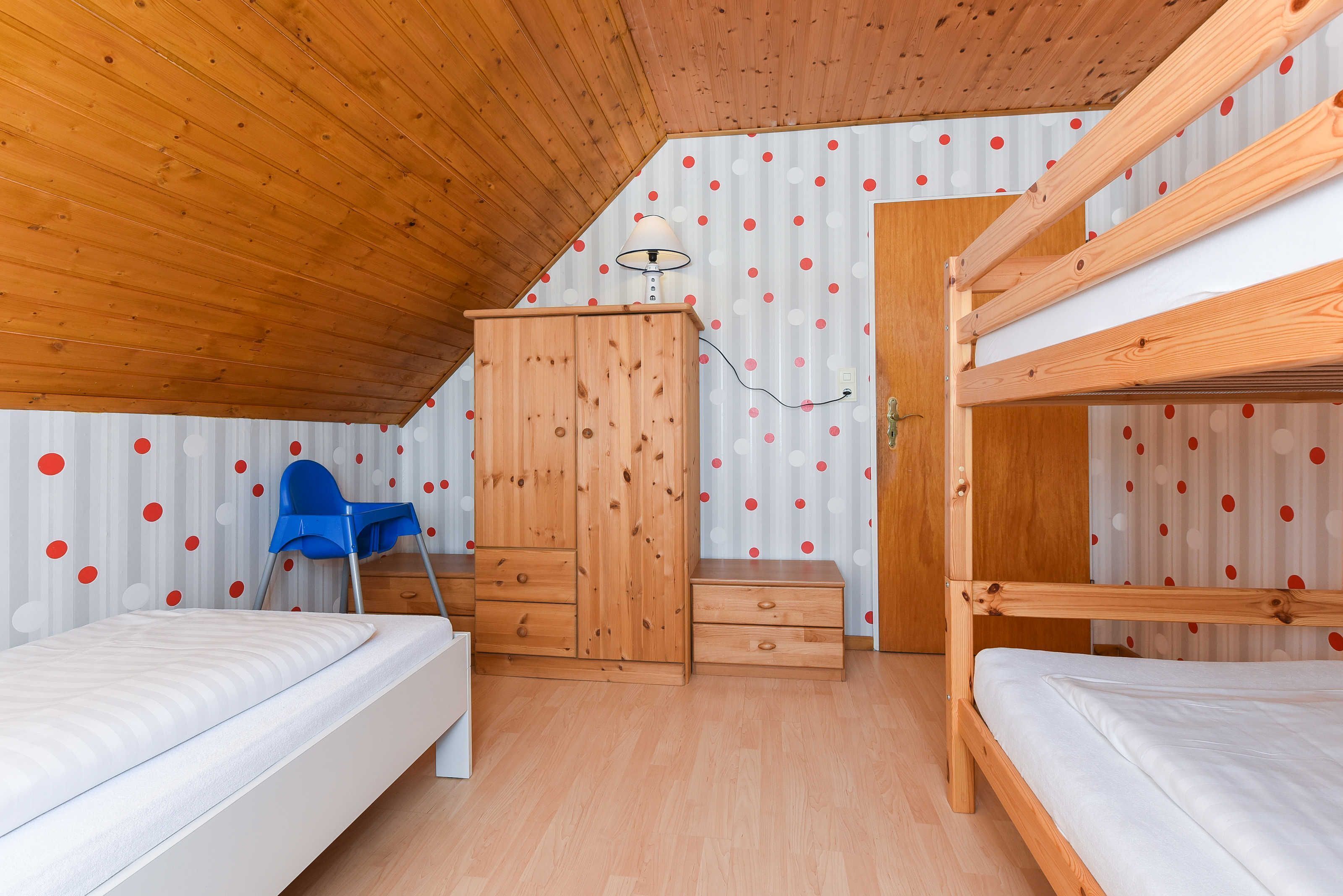 A room with a bunk bed, a desk, a chair, and a wardrobe.