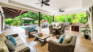 Un espacio abierto para la sala con piscina, asientos al aire libre y área de cocina.