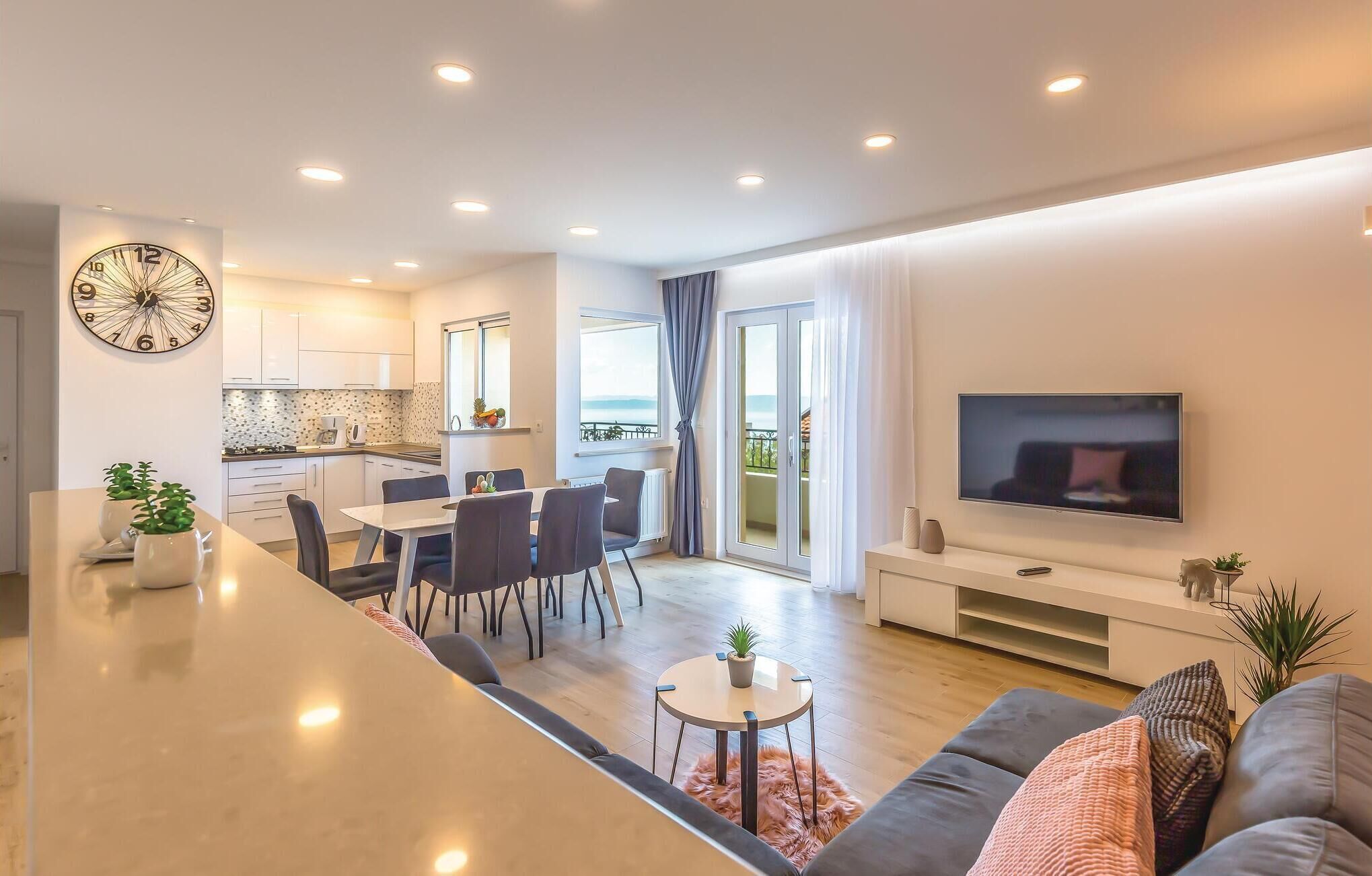 A modern apartment with a kitchen, dining area, living room, and balcony.