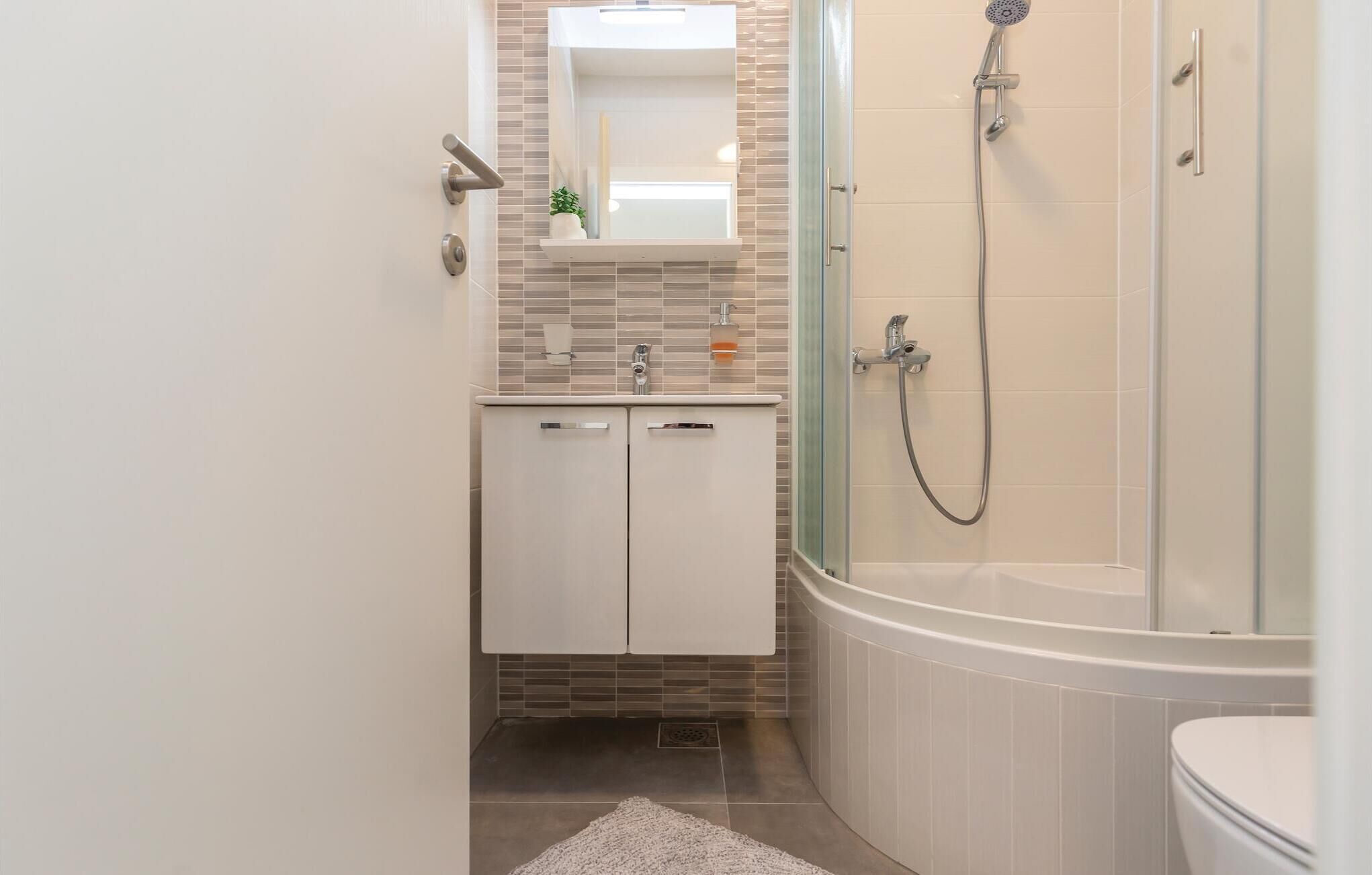 Een moderne badkamer met een douchecabine, een vrijstaand bad en een witte wastafel met een spiegel erboven.