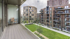 Un edificio de apartamentos moderno con varios balcones y un pequeño patio.
