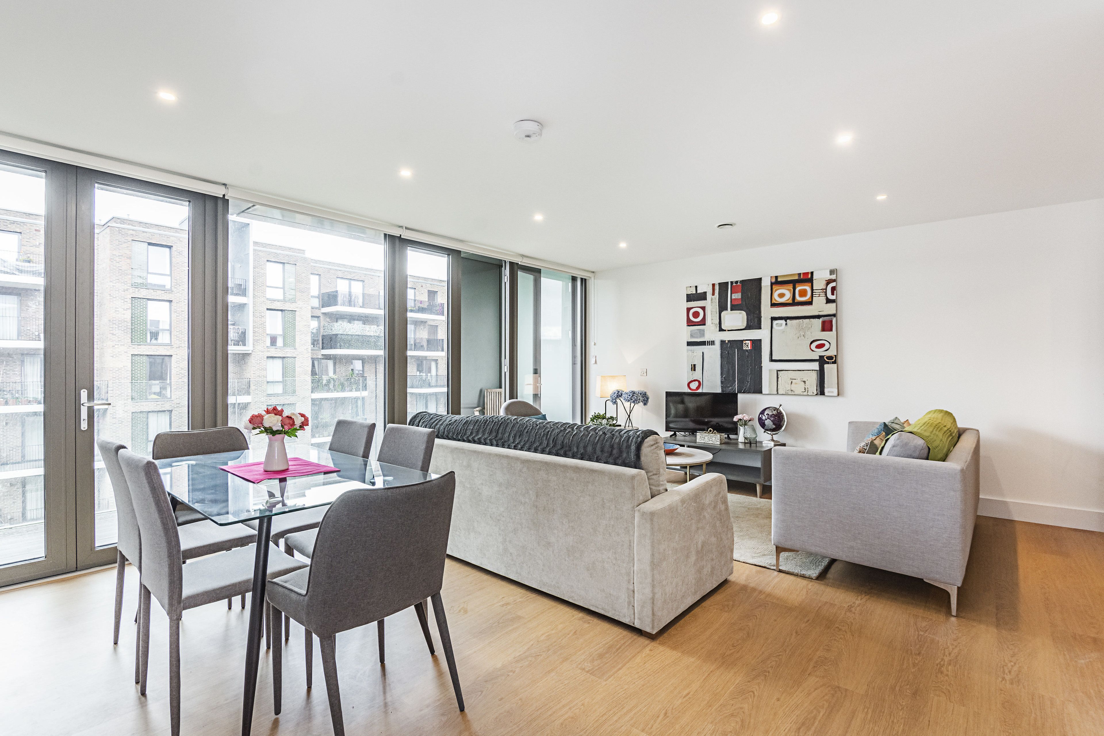 A modern apartment with a dining area, living room, and a large window offering a city view.
